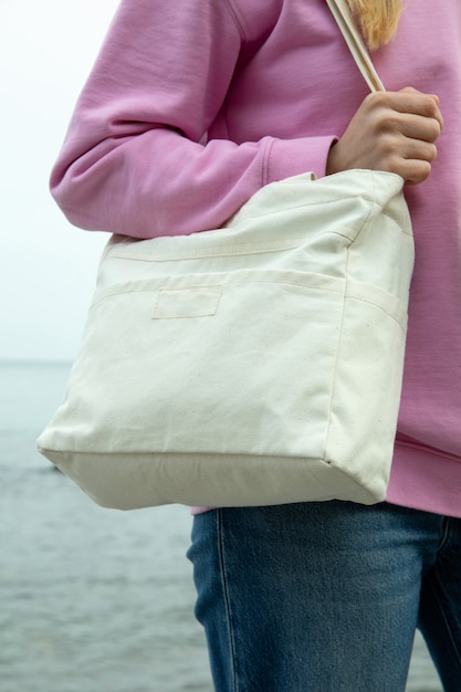 Young woman hold stylish eco bag against sea