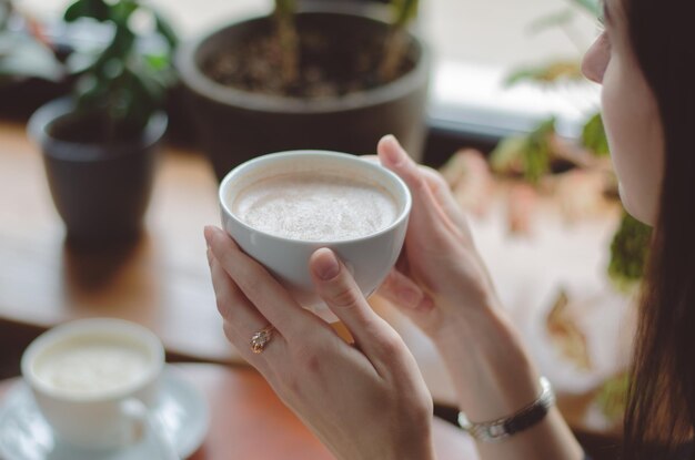 写真 彼女の手でコーヒーのマグカップを保持している若い女性