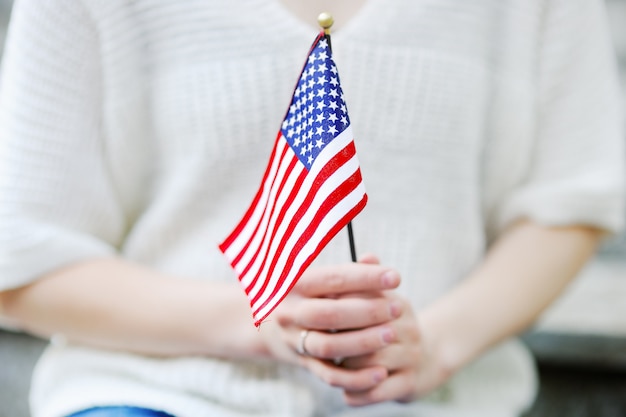 Giovane donna che tiene la bandiera americana. concetto di independence day.