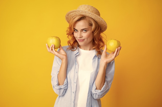 陽気で官能的な顔でセクシーな表情でカメラを見ているリンゴを保持している若い女性