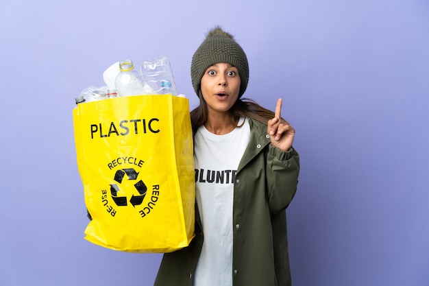 プラスチックでいっぱいのバッグを持っている若い女性は、指を持ち上げながら解決策を実現しようとしています