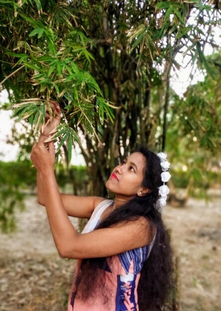 Foto giovane donna con le foglie di bambù in piedi sul campo