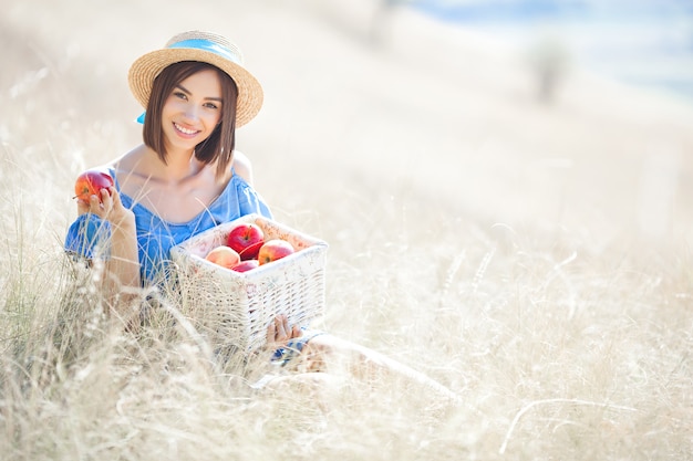 Молодая женщина держит корзину с яблоками