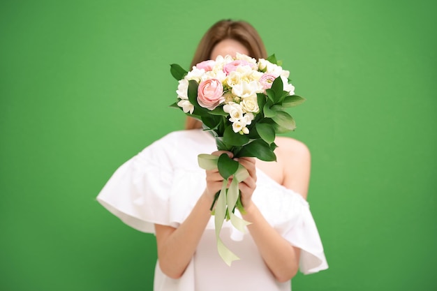 색상 배경에 흰색 프리지아가 있는 아름다운 꽃다발을 들고 있는 젊은 여성