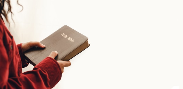 A young woman holding the Bible on white background close up