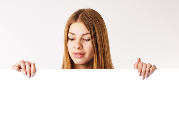 Young woman holding a big billboad, looking down on it.