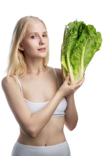 Young woman holding big bunch of fresh lettuce. Green salad leaves in hands of woman. Healthy clean eating concept. Vegan, vegetarian food. Copy space.