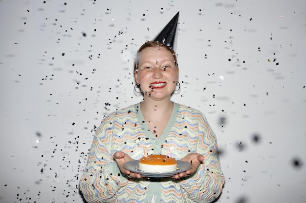 Foto giovane donna che tiene la torta di compleanno con doccia di coriandoli