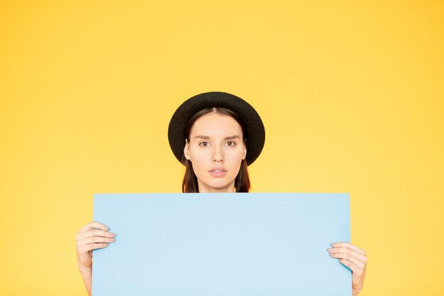 Young woman holding a blank poster