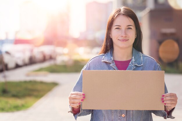 Young woman holding blank sign in her hands and smiles