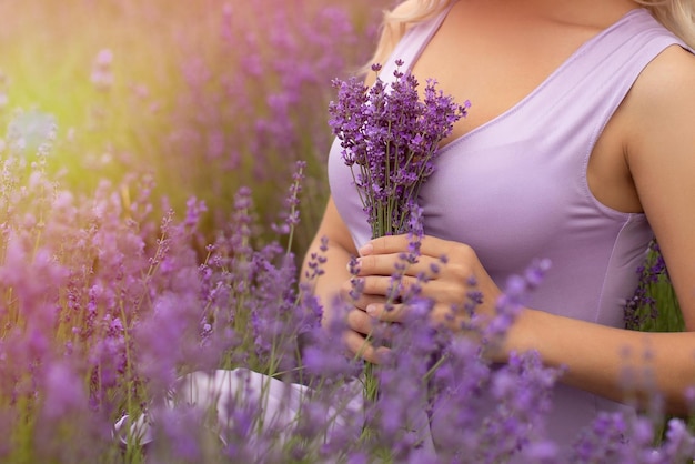 Young woman holding bouquet of lavender flowers in field