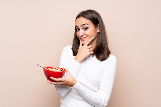 Young woman holding a bowl of cereals and thinking