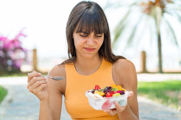 Young woman holding a bowl of fruit at outdoors