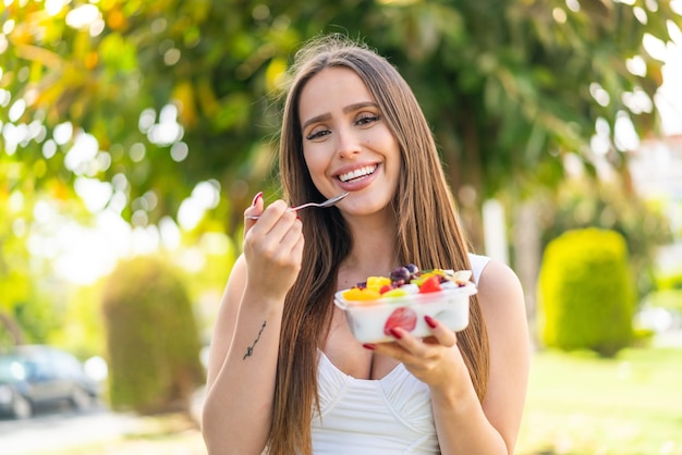 Foto giovane donna che tiene una ciotola di frutta all'aperto