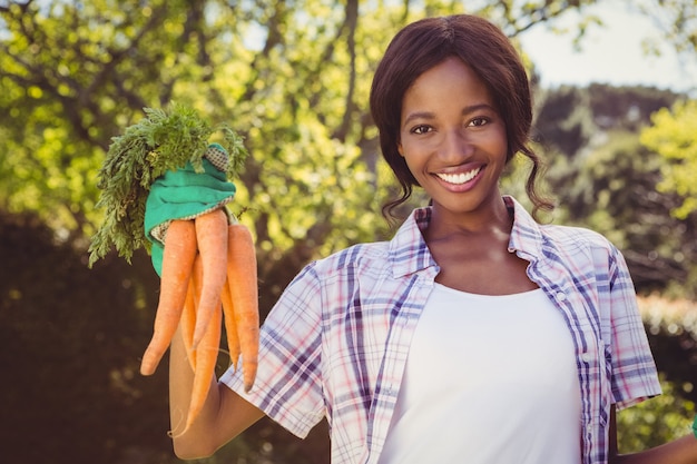 Young woman holding bunch of carrots