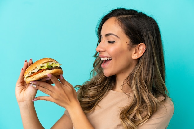 Молодая женщина, держащая гамбургер на изолированном фоне