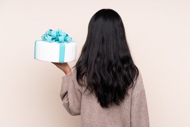 Young woman holding cake over isolated wall