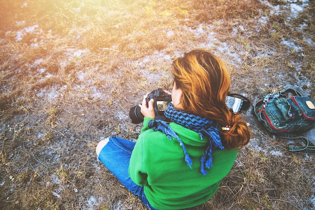 写真 陸に座っている若い女性がカメラを握っている