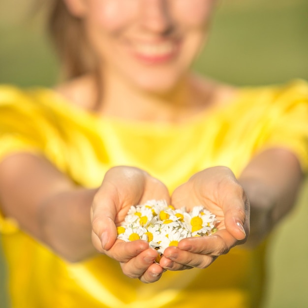 Young woman holding camomile in palms