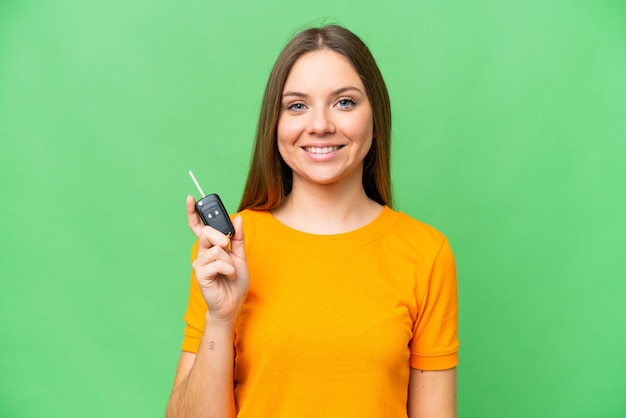 Young woman holding car keys over isolated chroma key background smiling a lot