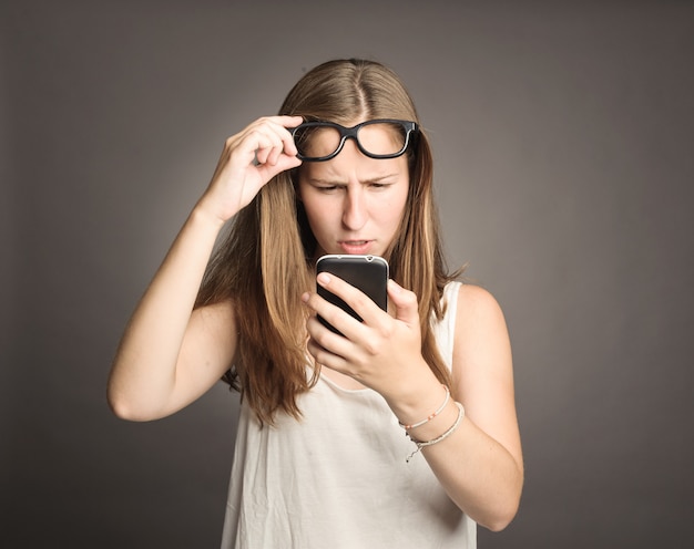 Young woman holding a cellular on gray