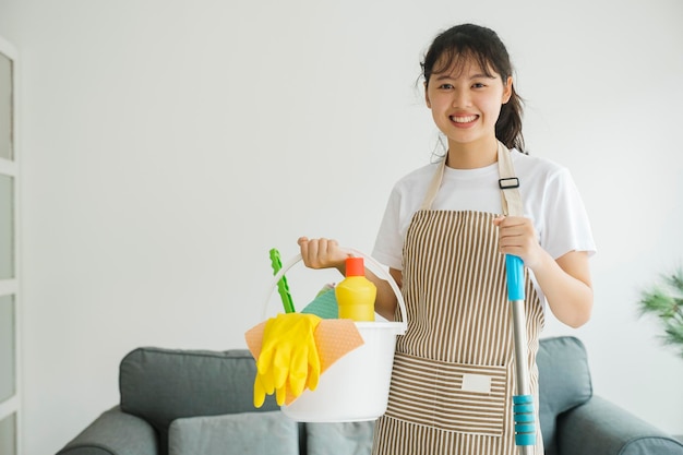 Photo young woman holding cleaning equipments ready for cleaning