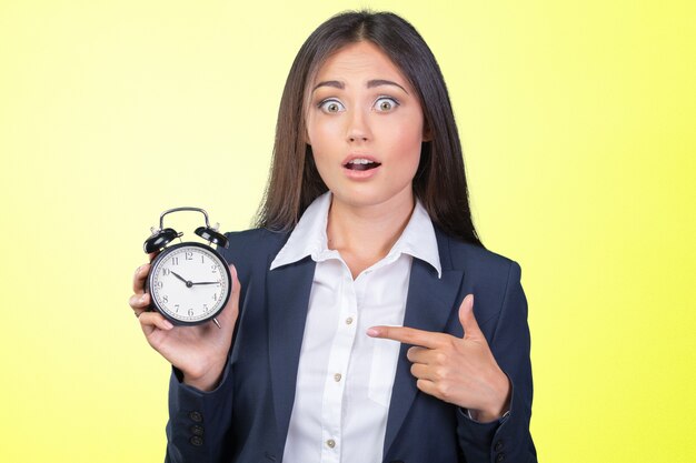 Young woman holding a clock. time management concept.