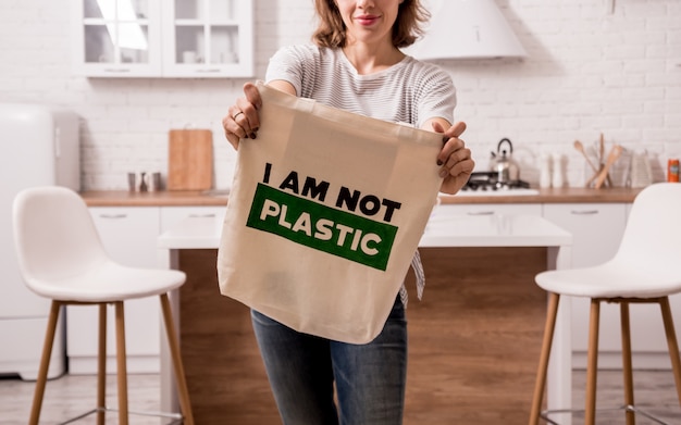 Young woman holding a cloth bag. At the kitchen. I am not plastic. Campaign to reduce the use of plastic bags. Zero waste