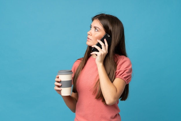 Young woman holding coffee to take away and a mobile