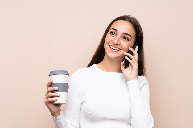 Молодая женщина, держащая кофе, чтобы забрать и мобильный