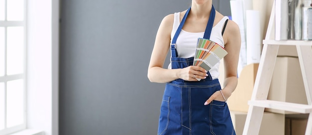 Young woman holding a color swatch with a painter painting