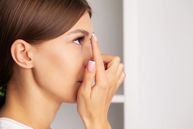 Young woman holding contact lens on finger.