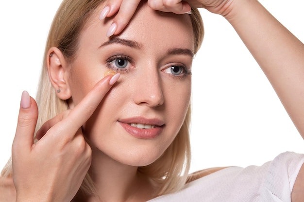 Young woman holding contact lens on index finger with copy space. Close up face of healthy beautiful woman about to wear contact lens. Eyesight and ophthalmology concept.