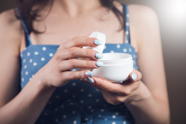 Young woman holding a container of cream