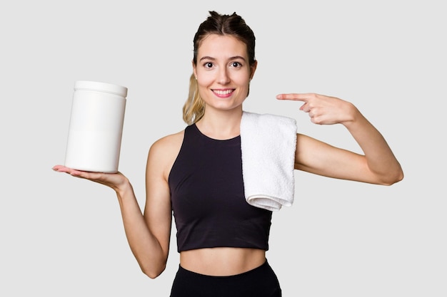 Young woman holding a container of protein powder dressed in sportswear