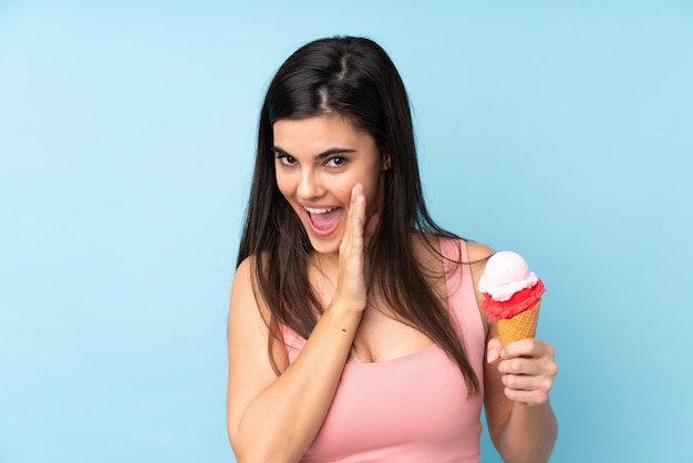 Young woman holding a cornet ice cream over isolated blue