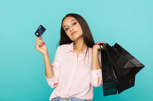 Young woman holding credit card and black bags and smiling. Black friday concept.