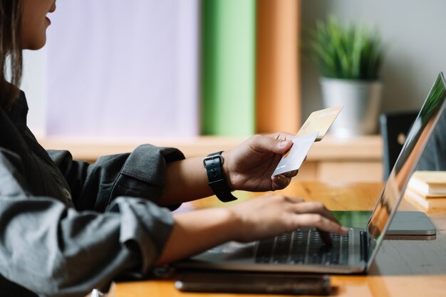 Giovane donna in possesso di carta di credito e utilizzando il computer portatile. concetto di acquisto online.