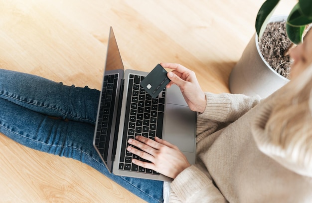 Young woman holding credit card and using laptop computer