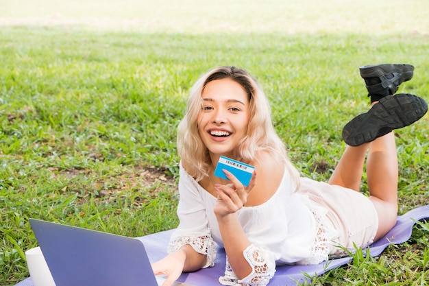 Young woman holding a credit card and using a laptop with online shopping concept