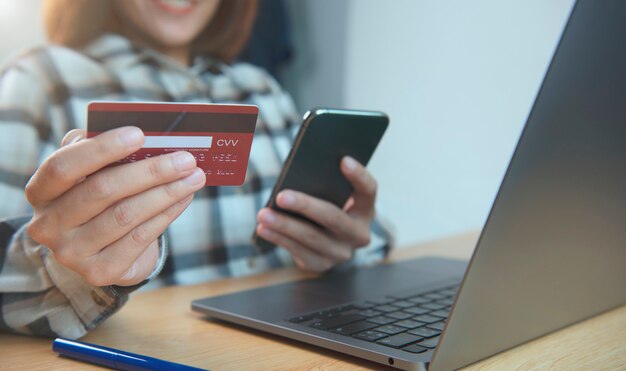 Young woman holding credit card and using smart phone buying online shopping. application mobile banking technology concept.