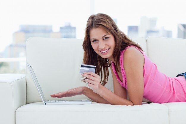 Young woman holding a credit card while showing a great smile