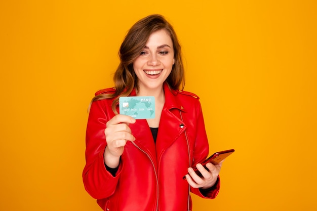 Young woman holding credit card with phone and smiling