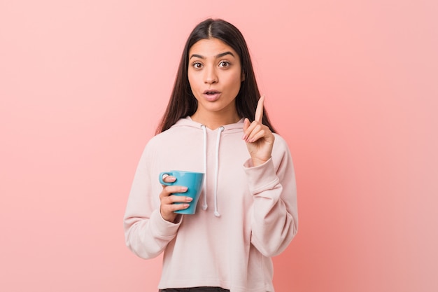 Young woman holding a cup having some great idea, concept of creativity.