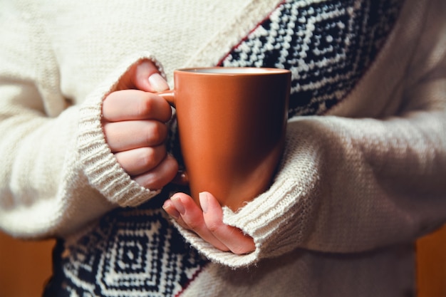 ホットコーヒーのカップを手に持った若い女性