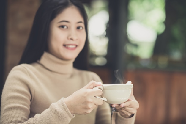 自然ビューでホットコーヒーのカップを保持している若い女性