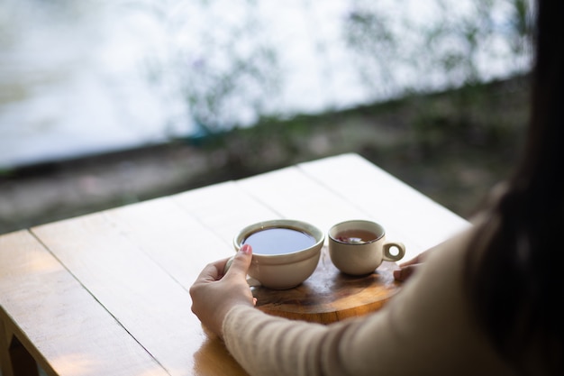 自然ビューでホットコーヒーのカップを保持している若い女性