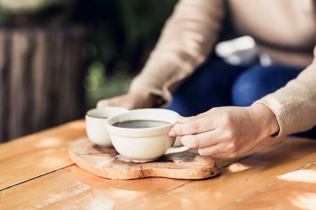 自然の景色でホットコーヒーのカップを保持している若い女性