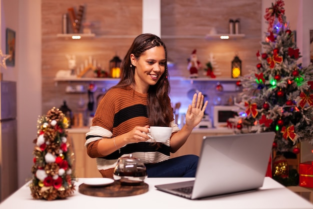 Young woman holding cup of tea using video call concept