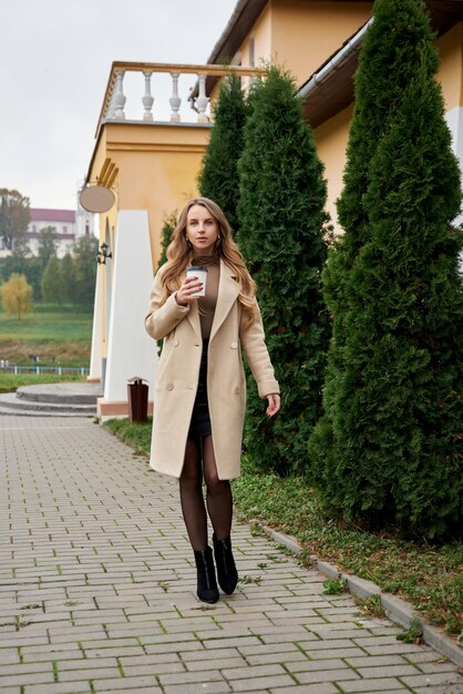 Young woman holding cup of warm coffee in park